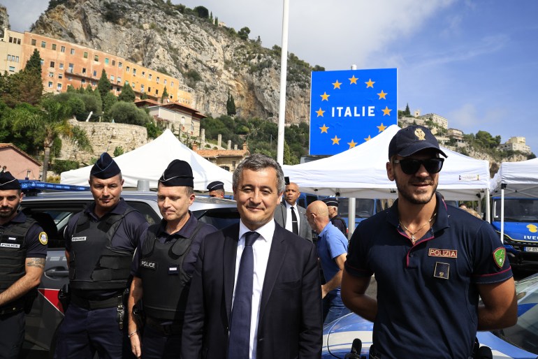 French Interior Minister Gerald Darmanin (C) poses with Italian and French police officers during his visit at Menton's border post on September 12, 2023. (Photo by Valery HACHE / AFP)