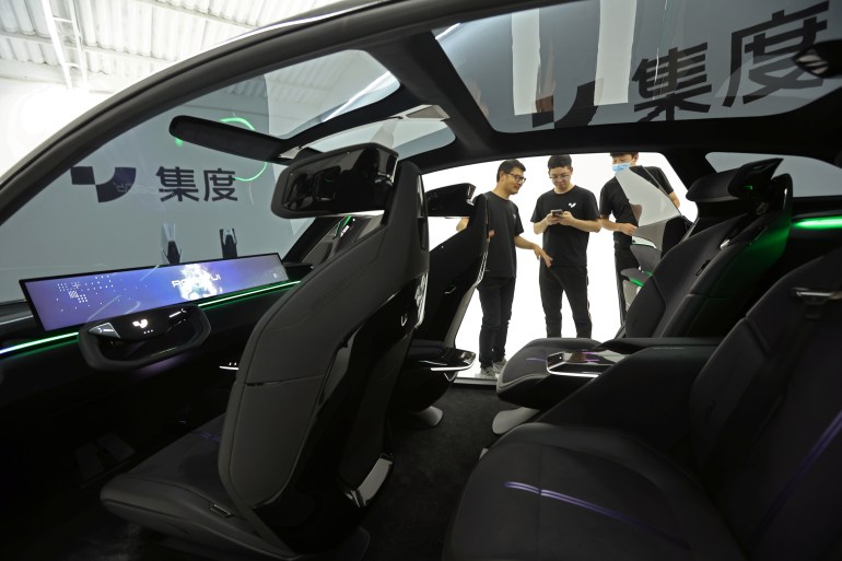 Staff members stand near ROBO-01, a "robot" concept car by Baidu's electric vehicle (EV) arm Jidu Auto, which is displayed during a media preview before its debut, in Beijing, China June 8, 2022. REUTERS/Tingshu Wang