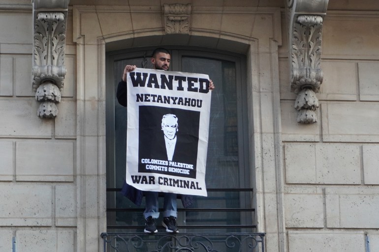 متظاهر يرفع لافتة كتب عليها "نتنياهو مطلوب للعدالة ومجرم حرب"، خلال مظاهرة مؤيدة لفلسطين في باريس، الإثنين 27 مايو