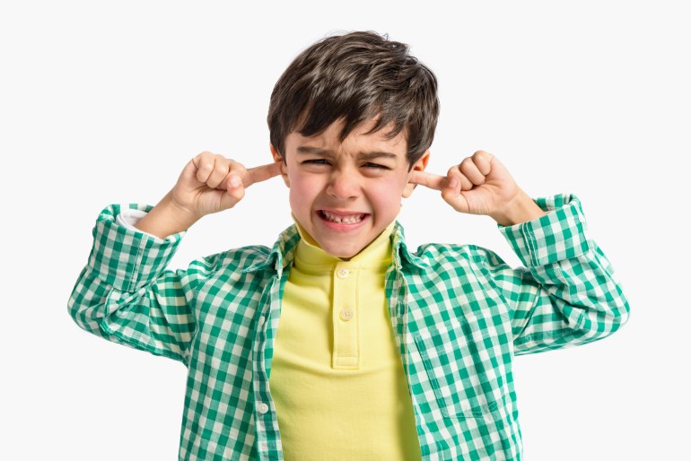 Boy covering his ears over white background.