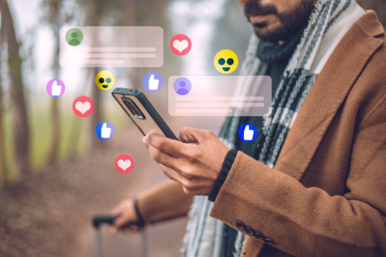 While traveling, a handsome man uses his smartphone to stay connected to social media, receiving notifications and commenting on posts.