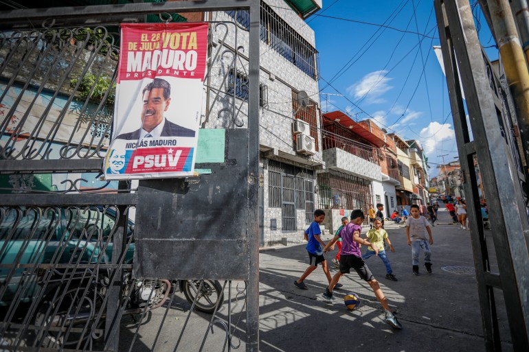 24 July 2024, Venezuela, Caracas: A poster with election propaganda from the PSUV party, President Maduro's government, hangs on a gate while children play soccer. Maduro has been in power since 2013 as the successor to Hugo Chávez. According to the German Foreign Office, the country with the world's largest known oil reserves lost around 80 percent of its gross domestic product between 2014 and 2020. Photo: Jeampier Arguinzones/dpa (Photo by Jeampier Arguinzones/picture alliance via Getty Images)