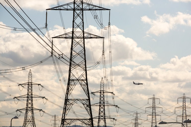 Pylons carrying electricity from Ratcliffe on Soar coal fired power station in Nottinghamshire, UK with a plane coming in to land at East Midlands airport.