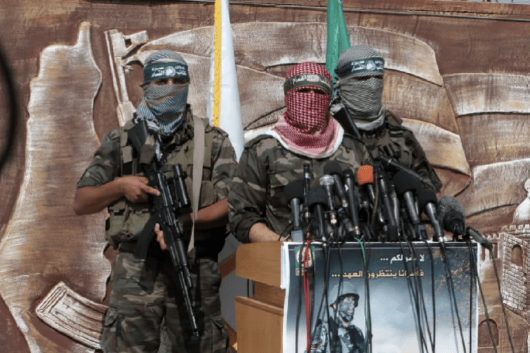 Abu Obaida (C), the spokesman for the Ezzedine Al-Qassam Brigades, the armed wing of Hamas, speaks during a news conference on October 18, 2012 at the Rafah border crossing with Egypt in the southern Gaza Strip to mark the first anniversary of a deal which saw the exchange of 1,027 Palestinian prisoners for captured Israeli soldier Gilad Shalit. The snatching of Israeli soldier Gilad Shalit in June 2006 by a group of Hamas militants and others sparked a more than five-year crisis for Israel, which finally ended on October 18, 2011. AFP PHOTO/SAID KHATIB (Photo by SAID KHATIB / AFP) (الفرنسية)