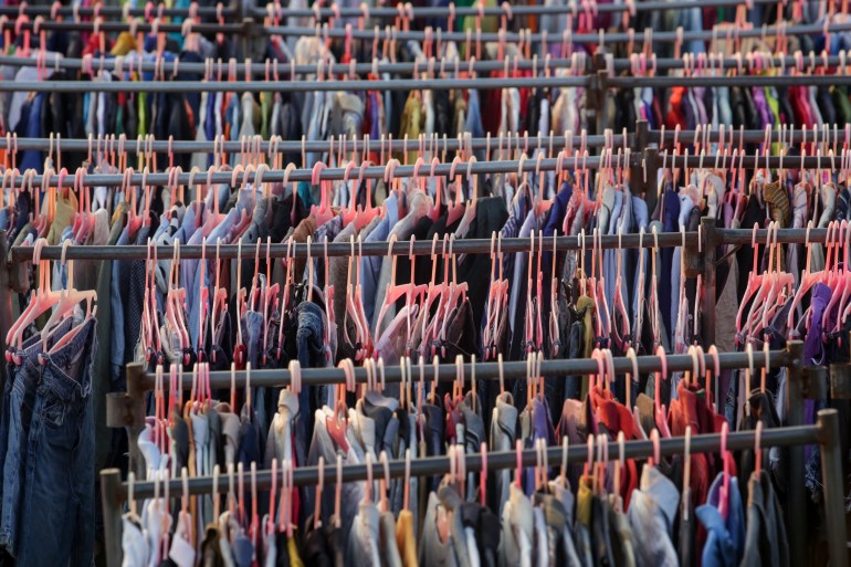 Huge selection of different used clothes for men, women and children on the rack in a second hand shop or thrift store. Concept of waste problem in fashion industry.