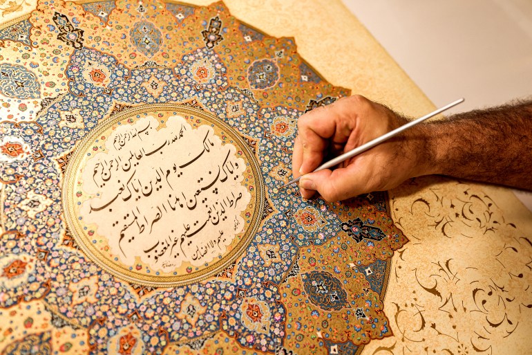 Mohammad Hossein Aghamiri, an artist who specialises in Persian miniatures, works on one of his pieces depicting al-Fatiha, the first chapter of the Koran (Islam's holy book), at his workshop in Tehran on June 5, 2024. - Iranian artist Mohammad Hossein Aghamiri sometimes labours for six months on a single design, very carefully -- he knows any crooked line could ruin his sketch. In the age of AI-assisted graphic design on computer screens, the centuries-old tradition of Persian illumination offers an antidote to rushing the creative process. (Photo by ATTA KENARE / AFP)