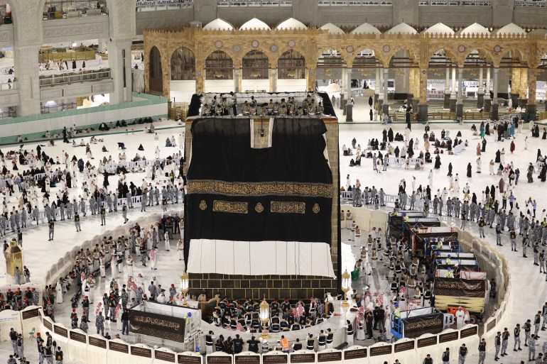 Saudi workers adjust the new Kiswa, the protective cover that engulfs the Kaaba which is made from black silk and gold thread and is embroidered with Koran verses, in Saudi Arabia's holy city of Mecca, on July 6, 2024. (Photo by Abdel Ghani BASHIR / AFP)