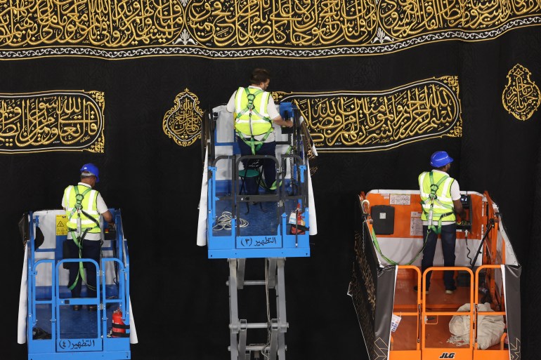 Saudi workers adjust the new Kiswa, the protective cover that engulfs the Kaaba which is made from black silk and gold thread and is embroidered with Koran verses, in Saudi Arabia's holy city of Mecca, on July 6, 2024. (Photo by Abdel Ghani BASHIR / AFP)