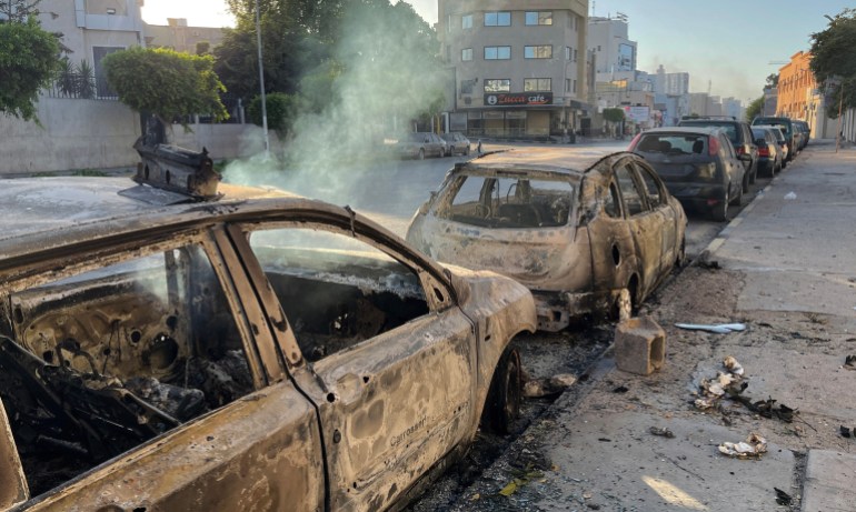 Damaged vehicles are pictured in a street in the Libyan capital Tripoli on August 27, 2022, following clashes between rival Libyan groups. - Clashes between backers of Libya's rival governments killed at least 13 people and damaged six hospitals in Tripoli, sparking fears that a political crisis could spiral into a major new armed conflict. (Photo by Mahmud TURKIA / AFP)