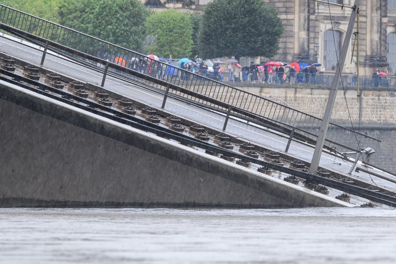 15 September 2024, Saxony, Dresden: Water from the Elbe flows over parts of the partially collapsed Carola Bridge, with onlookers on Brühl's Terrace in the background. The water levels continue to rise in Saxony. The highest alert level is likely to be reached on the Elbe in just two days. Photo: Robert Michael/dpa (Photo by Robert Michael/picture alliance via Getty Images)