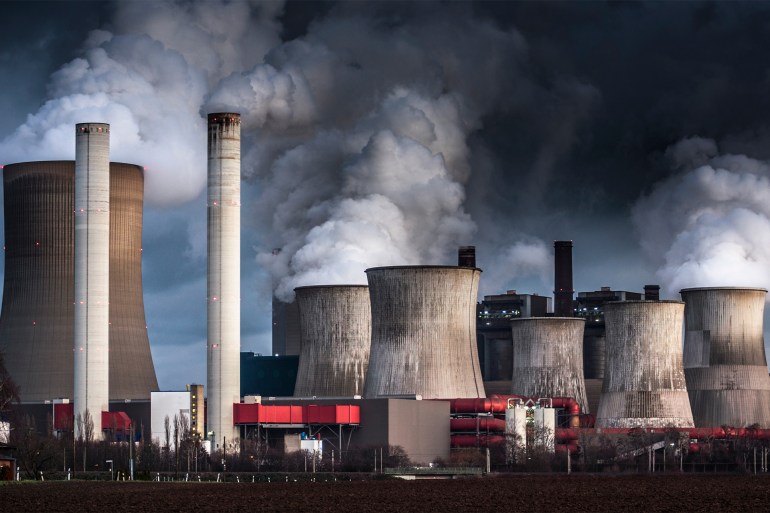 Air Pollution by coal fired power station - stock photo Chimneys and cooling towers from a coal fired power station releasing smoke and steam into the atmosphere. The power plant is also releasing CO2 which contributes to global warming and climate change.