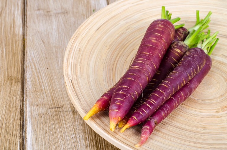 Sliced purple carrot on wooden background. Studio Photo