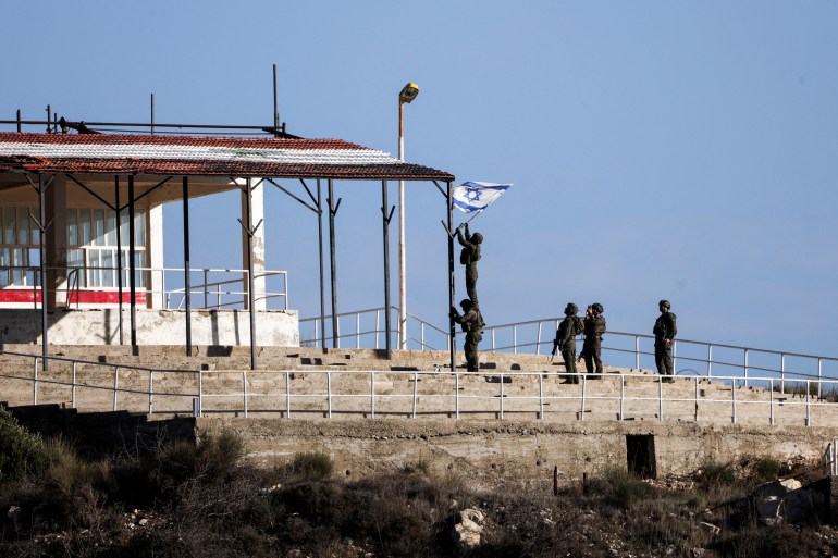 Israeli soldiers attempt to place an Israeli flag in Syria, after the ousting of Syria's Bashar al-Assad, as seen from Majdal Shams in the Israeli-occupied Golan Heights, December 23, 2024. REUTERS/Ronen Zvulun TPX IMAGES OF THE DAY