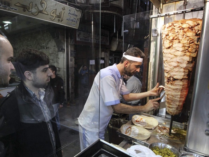 A chef slices Shawarma along a street in Damascus in this November 12, 2012 file photo. MiG warplanes roar low overhead to strike rebels fighting to oust President Bashar al-Assad on the fringes of Damascus, while artillery batteries pound the insurgents from hills overlooking a city divided between all-out war and a deceptive calm. That is one Damascus. In the other, comprising the central districts of a capital said to be the oldest continually inhabited city in the world, the restaurant menus are full, the wine is cheap and the souks are packed with shoppers. Employees report for work, children go to school and shops are open, seemingly undeterred by the din and thud of war. Picture taken November 12, 2012. To match SYRIA-CRISIS/DAMASCUS REUTERS/Muzaffar Salman/Files (SYRIA - Tags: SOCIETY FOOD BUSINESS POLITICS CONFLICT CIVIL UNREST)