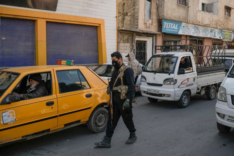 Security forces of the newly formed Syrian government inspect cars in a security checkpoint in the Karm Az-Zeitoun neighborhood of Homs, Syria, Thursday, Dec. 26, 2024. (AP Photo/Leo Correa)