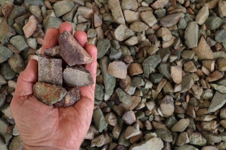 Rare earth (earths) ore held in open hand. Critical minerals, used for permanent magnets, aerospace alloys, specialty glass, electronic equipment, electric motors for electric vehicles, wind turbines