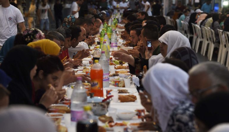 More than 1.200 people have broken the Ramadan fast with a giant meal served on Friday evening in Algiers on June 24, 2016. Along the Mourad Didouche Avenue, near the Grande Poste, hundreds of men and women of all ages, alone or with their families, famous and anonymous, gathered around big tables set on this street closed to traffic for this occasion. (Photo by Farouk Batiche / AFP)