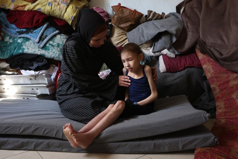 Shuruq Ayyad consoles her 12-year-old daughter Rahaf, who is suffering from malnutrition, at a school-turned-shelter in al-Rimal in central Gaza City on May 4, 2025.