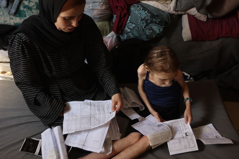 Shuruq Ayyad and her 12-year-old daughter Rahaf, who is suffering from malnutrition, look at medical reports at a school-turned-shelter in al-Rimal in central Gaza City on May 4, 2025.