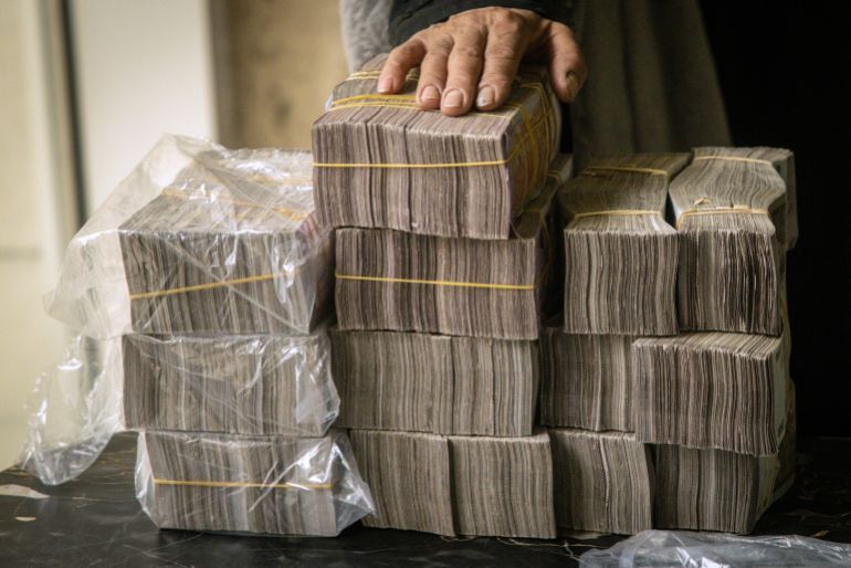 DAMASCUS, SYRIA - DECEMBER 24: A woman holds a stack of Syrian pounds after exchanging U.S dollars at the Central Bank Of Syria on December 24, 2024 in Damascus, Syria. On December 8, rebel forces in Syria retook the capital and several other cities from longtime ruler Bashar al-Assad, who fled the country for Moscow. The fall of the Assad regime marks a new chapter for Syria, which has been mired in a multi-party civil war since 2011, sparked by the Arab Spring uprisings. (Photo by Chris McGrath/Getty Images)