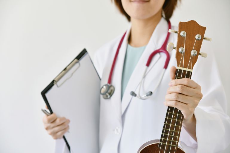 Doctor hand holding ukulele (musical instrument), Music therapy concept. (Selective Focus)