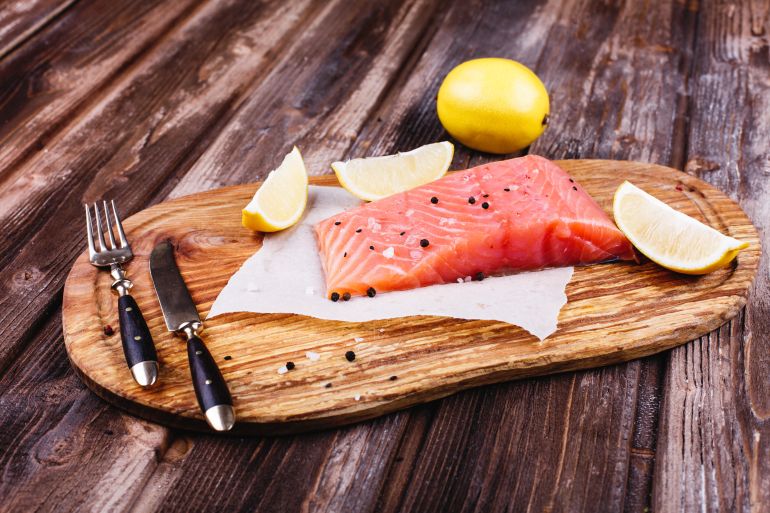 التونة أم السلمون.. أي منهما يناسب أسلوب حياتك؟ Healthy and fresh food. Raw salmon served with lemons and knives on wooden board المصدر: فريبك