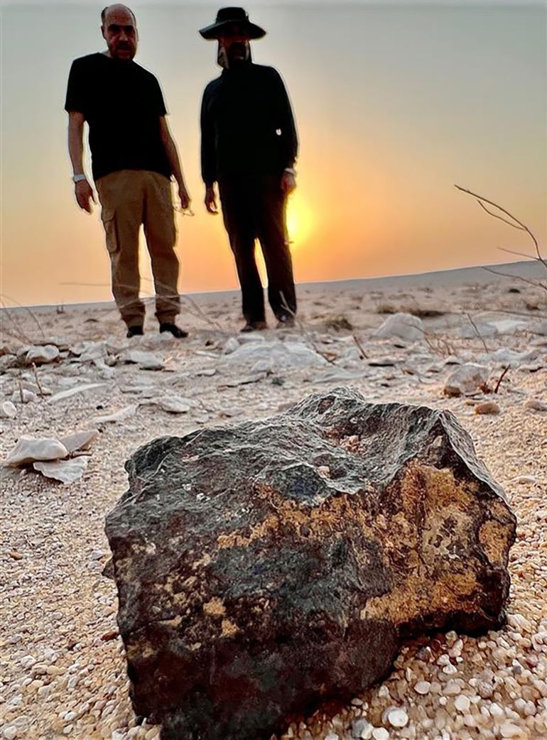 ****داخلية**** هاني الضليع وخالد القيسية يقفان بالقرب من أحد النيازك التي عثرا عليها أثناء رحلة بحث في إحدى الصحارى